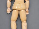 a close up of a doll laying down on a gray surface