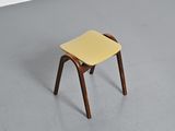 a small wooden stool with a yellow seat in a room