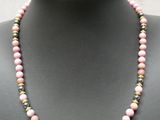 un collier de perles roses sur un mannequin, rehaussé de touches dorées