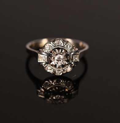 an antique engagement ring with a center stone surrounded by small diamonds