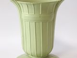 un vase vert posé sur une table blanche