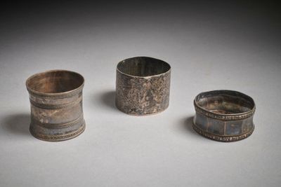 trois pièces d'argenterie anciennes sont posées sur une surface blanche