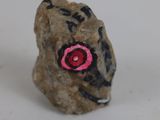 a small rock with a pink flower on it