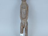 une vieille statue en bois représentant un homme, avec une étiquette sur la poitrine