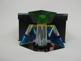 une image représentant un objet en verre vert et noir posé sur une surface blanche