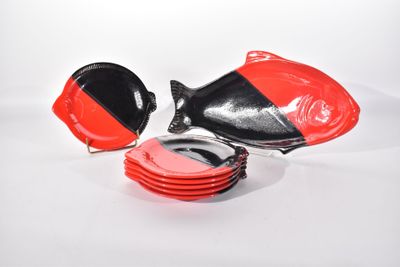 une assiette rouge et noire sur laquelle est posé un poisson