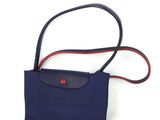 sac à main bleu marine avec une bandoulière rouge et un bouton rouge