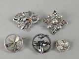 six silver brooches with flowers and leaves on them on a white surface