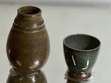 two small vases sitting on a table next to each other