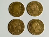 four gold coins sitting on top of each other on a white surface