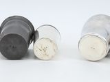 four salt and pepper shakers are lined up on a white surface