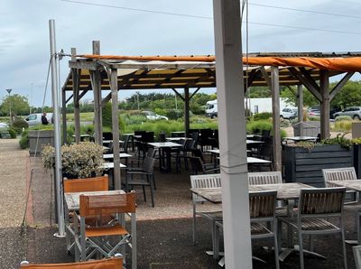 de nombreuses tables et chaises sous un toit en pergola