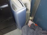 un climatiseur bleu posé par terre à côté d'un meuble noir