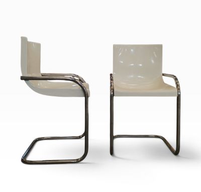 deux chaises blanches placées l'une à côté de l'autre sur une surface blanche