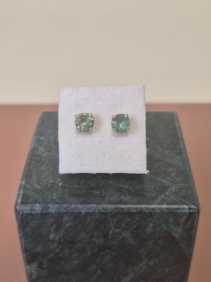 a pair of green earrings sitting on top of a black box