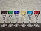 six different colored wine glasses are lined up on a table