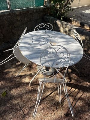 une table et des chaises blanches à l'ombre d'un arbre