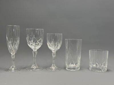 four wine glasses and a glass tumbler are lined up on a table