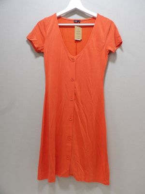 an orange dress hanging on a hanger against a white wall