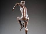 bronze statue of a woman sitting on a pedestal with her legs crossed