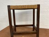 a wooden stool sitting on top of a table next to a wall