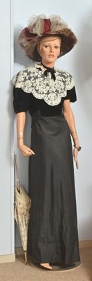 un mannequin vêtu d'une robe noire et d'un chapeau