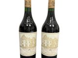 two bottles of red wine sitting next to each other on a white surface