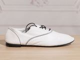 white leather shoes with black laces on a wooden table