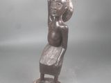 statue d'une femme assise sur une chaise, les bras levés