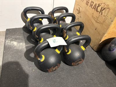 Plusieurs haltères sont alignés sur le sol d'une salle de sport