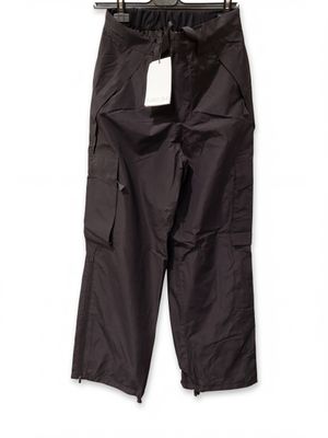 un pantalon cargo noir suspendu à un cintre sur un mur blanc