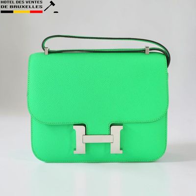 un sac à main vert muni d'une poignée métallique sur fond blanc