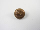 un gros plan d'un petit bouton en bronze sur une surface blanche