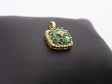 an emerald and diamond pendant on a black leather surface