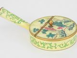 une boîte jaune et verte munie d'une poignée, posée sur une surface blanche
