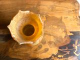 a yellow vase sitting on top of a wooden table