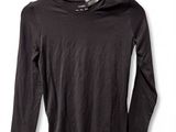black long - sleeved shirt hanging on a hanger on a white wall