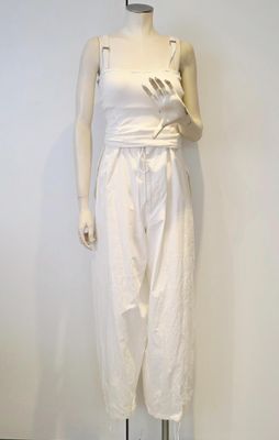 un mannequin vêtu d'un haut et d'un pantalon blancs, posé sur un socle