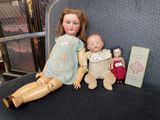 two dolls sitting next to each other on a chair