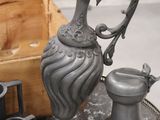 a silver pitcher sitting on top of a table next to other items