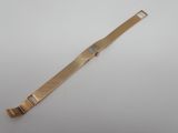 gros plan d'une montre en or sur une surface blanche