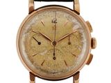 a close up of a gold watch with a black leather strap