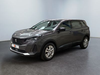 Une voiture grise est garée dans une pièce au sol noir.