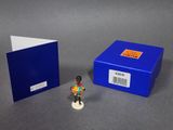 a small figurine stands next to a blue box and a small book