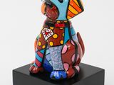 ceramic sculpture of a dog wearing a colorful shirt on a black base
