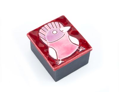 une petite boîte rouge ornée d'un oiseau rose