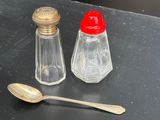 deux salières et poivrières et une cuillère posées sur une table