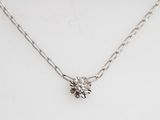 a close up of a silver necklace with a flower on it