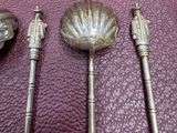 three silver spoons and a spoon rest on a leather surface