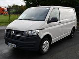 La camionnette blanche est garée sur le parking près de la pelouse.